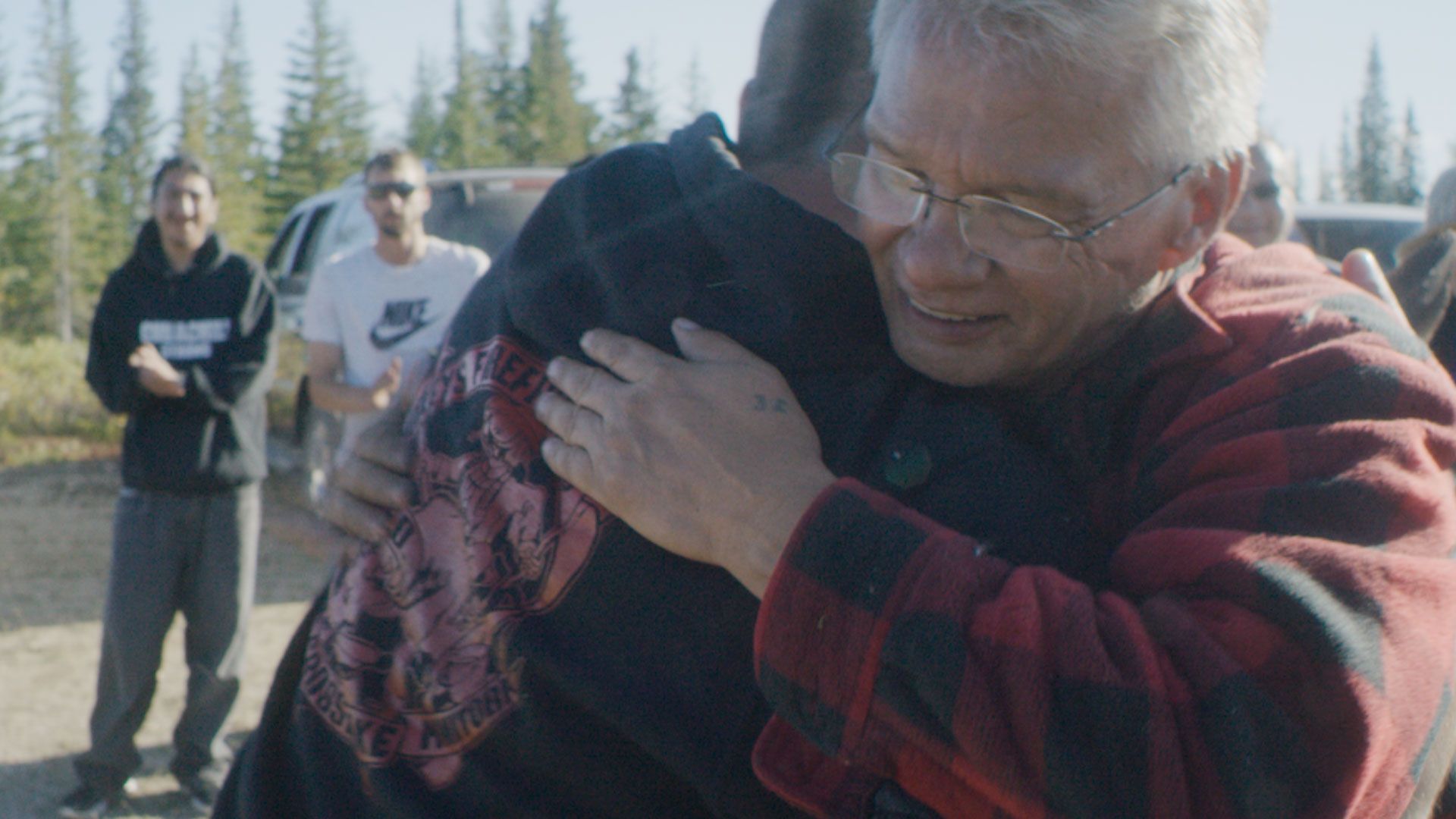 Still from a video showing two Indigenous people embracing.